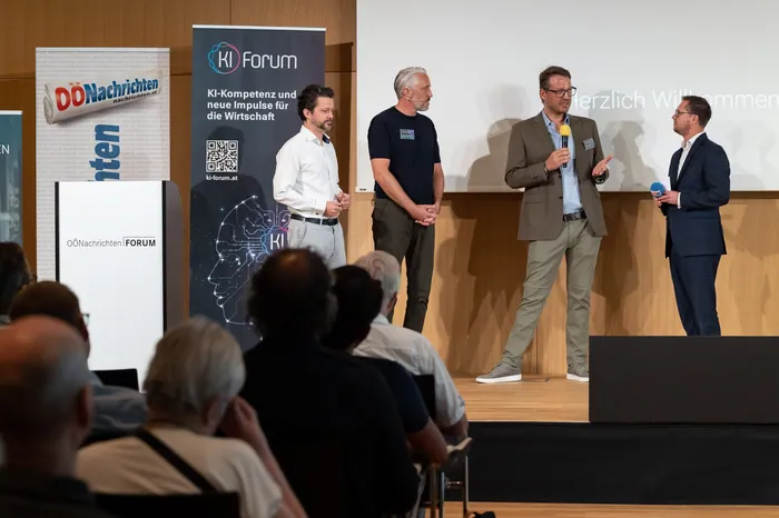 Panel discussion on stage with KI-Forum banners